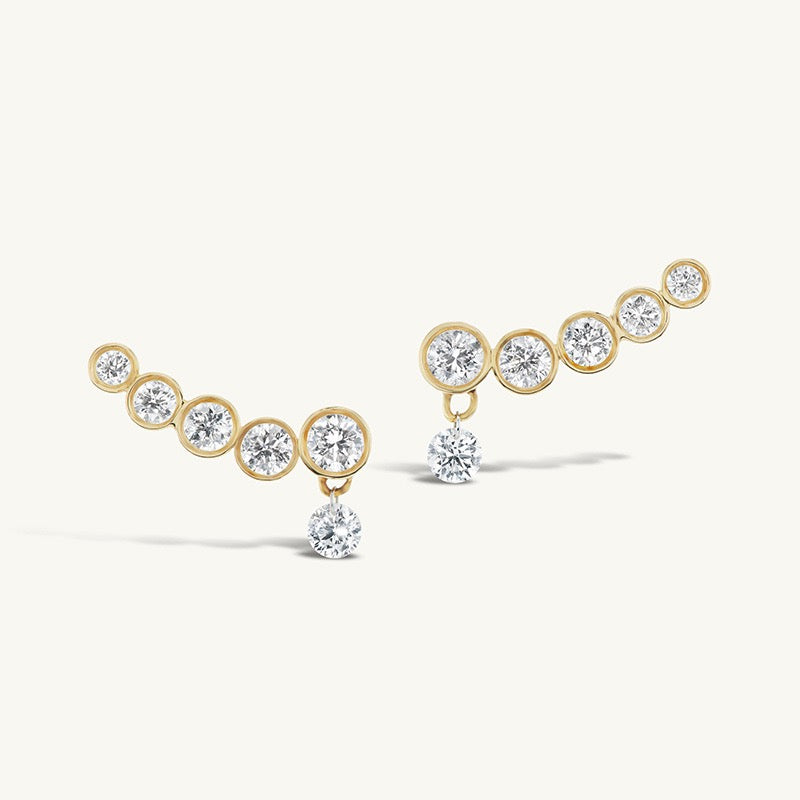 Line Earrings in gold with five graduated bezel-set zirconia stones and a dangling round stone