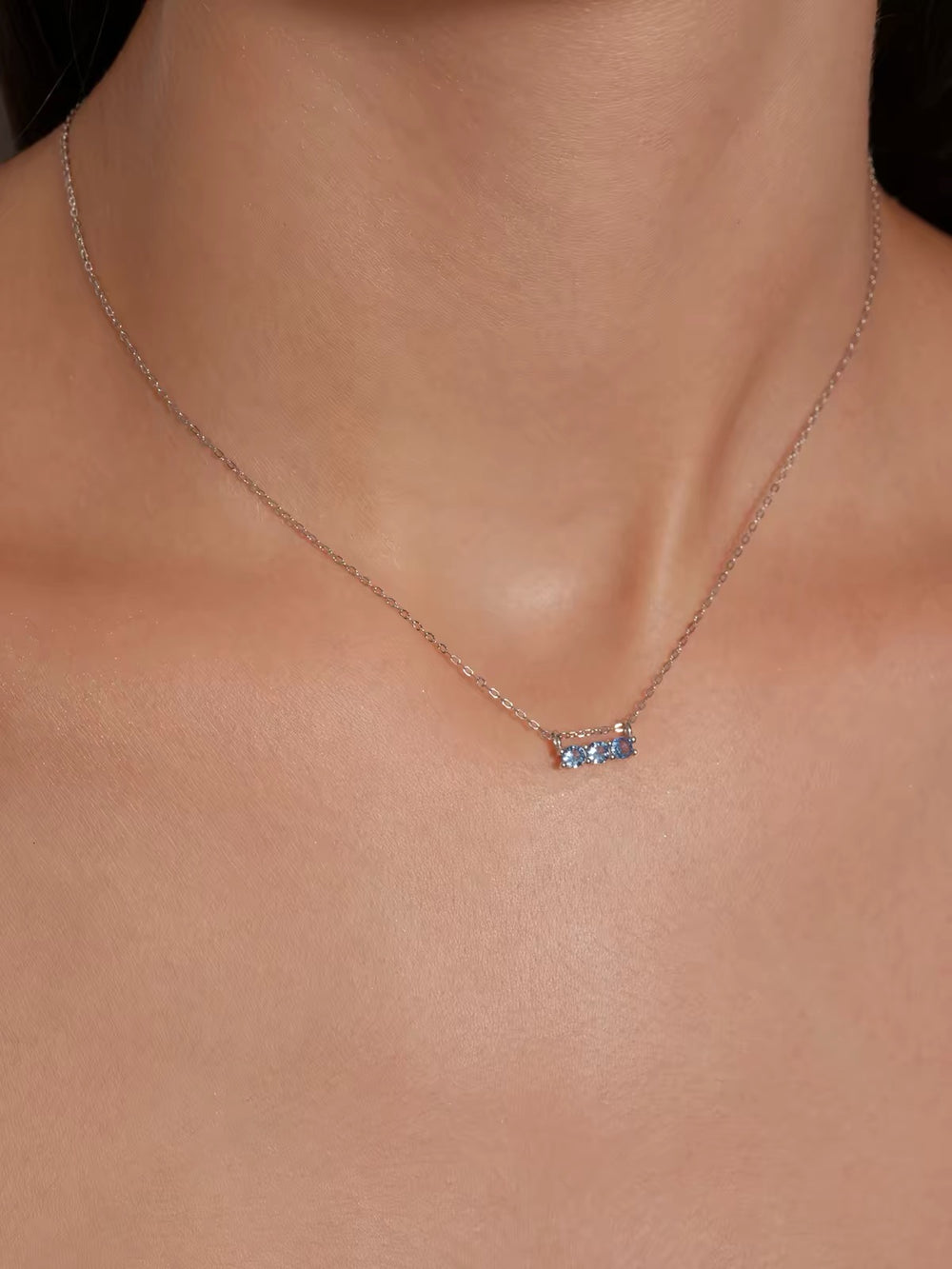 Close-up model view of blue three-stone necklace