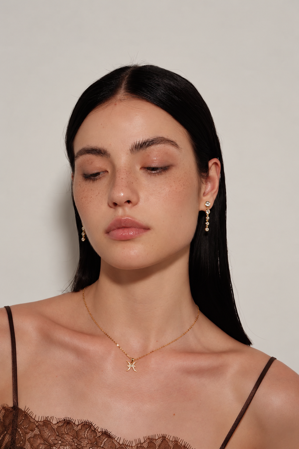 Model wearing Cascade Earrings in gold with a downward gaze