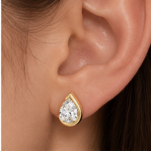 Detailed ear close-up of Goutte Éclat gold pear-shaped stud earring