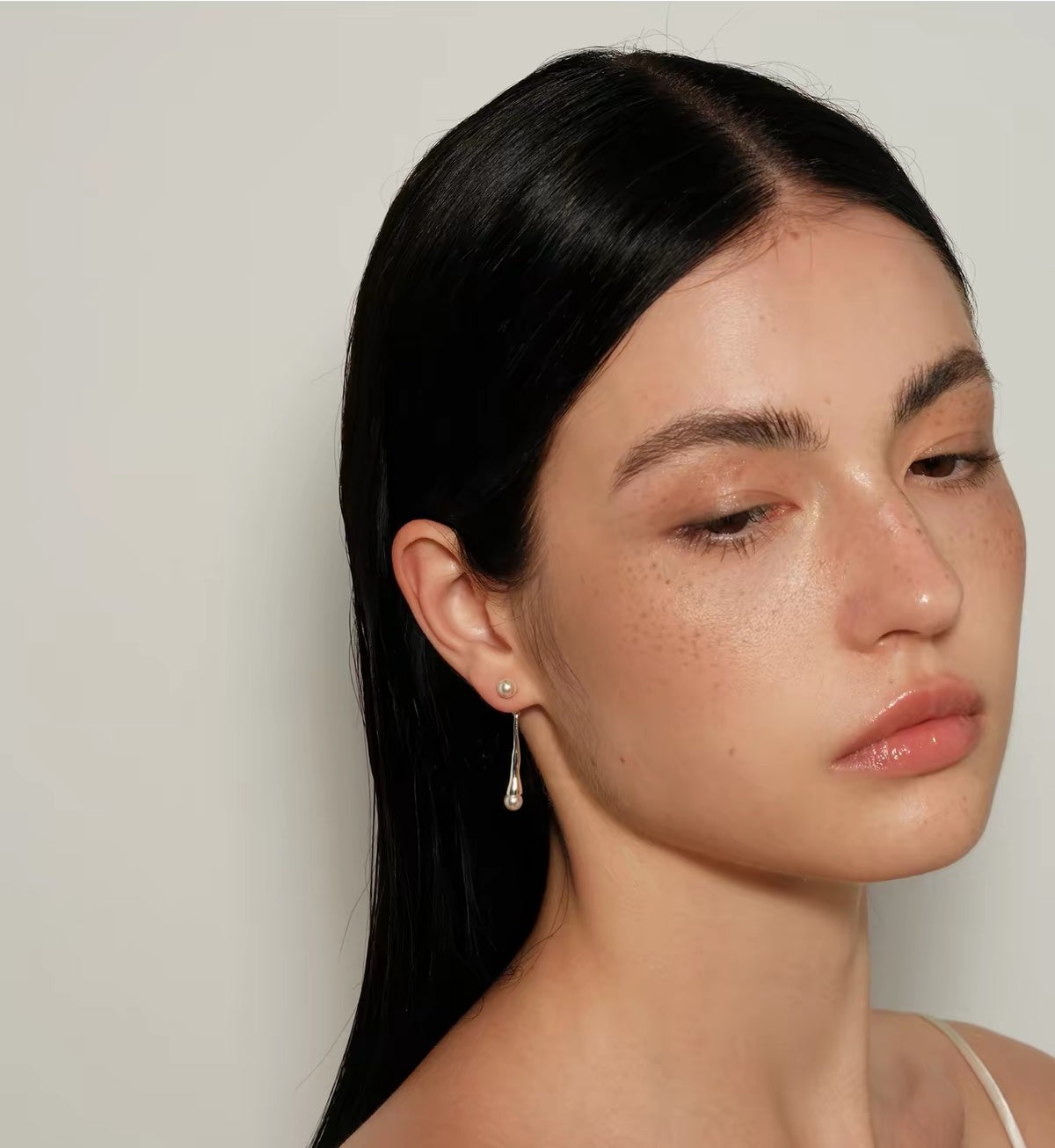 Model wearing Perle Fluide drop earrings, angled portrait